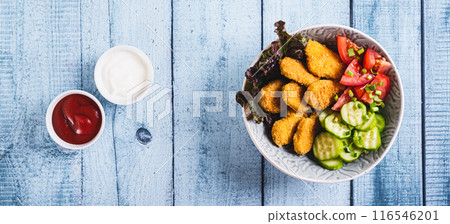 Fried chicken nuggets, cucumber and tomato in a bowl on the table top view web banner 116546201