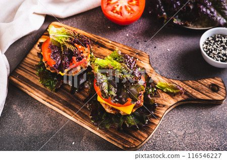 Juicy keto burgers on fresh lettuce leaves of cutlet, tomato and cheese on a board on the table 116546227