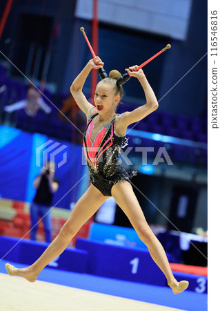 Female Rhythmic Gymnast Demonstrating Agility and Elegance in Midair Leap with Clubs Female Rhythmic Gymnast Demonstrating Agility and Elegance in Midair Leap with Clubs 116546816