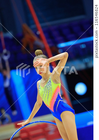 A skilled Rhythmic Gymnastics athlete performs with a hoop at a competitive arena A skilled Rhythmic Gymnastics athlete performs with a hoop at a competitive arena 116546824