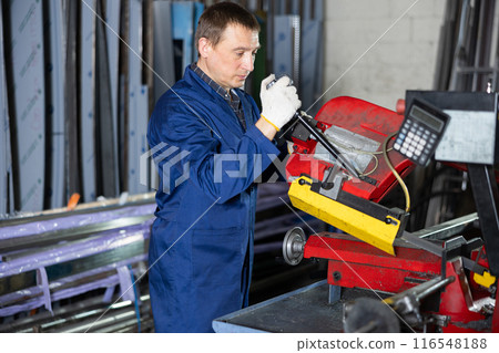 Worker works on a machine for cold cutting of round and square pipes 116548188