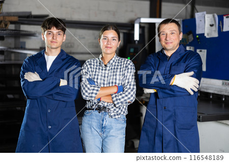 Group of smiling workers posing together in metalworking workshop 116548189