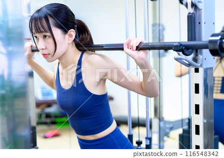Women working out at the gym, barbell squats, women doing muscle training, workout, hip-up, trimming Women working out at the gym, barbell squats, women doing muscle training, workout, hip-up, trimming 116548342