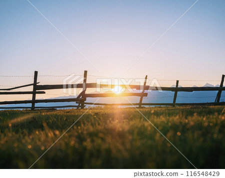 Wooden fence silhouetted against a mountain range at sunset Wooden fence silhouetted against a mountain range at sunset 116548429