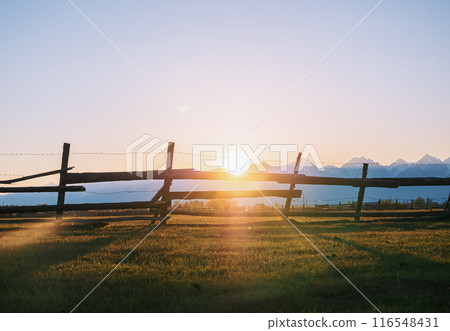 Wooden fence silhouetted against a mountain range at sunset 116548431