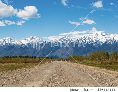 A winding gravel road leading toward snow-capped mountains A winding gravel road leading toward snow-capped mountains 116548443