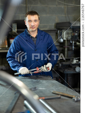 Adult man posing with vice in workshop 116548767