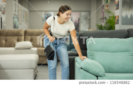 Woman in furniture center chooses best sofa for her apartment 116548862
