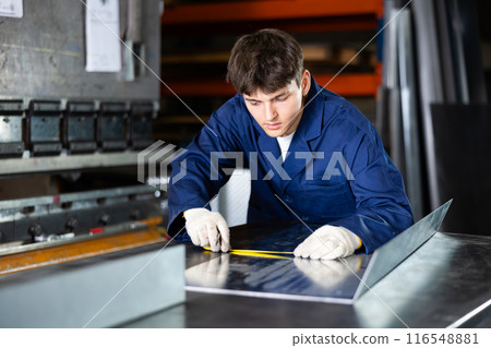 Guy measuring sheet of metal with tape measure Guy measuring sheet of metal with tape measure 116548881