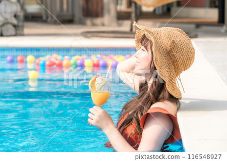年輕的亞洲女性在度假村度假時在泳池裡喝熱帶飲料 116548927