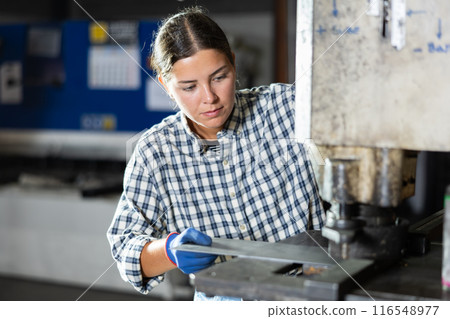 Girl learns to operate a hydraulic press to punch holes in metal plate Girl learns to operate a hydraulic press to punch holes in metal plate 116548977