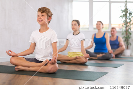 Happy preteen boy practicing lotus pose of yoga with his family 116549057