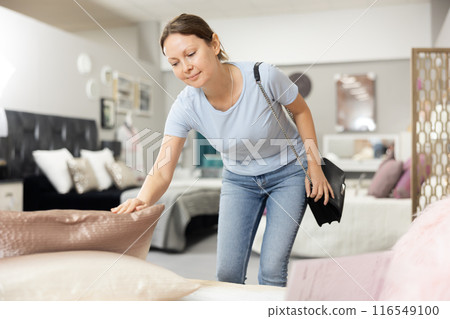 Positive woman chooses modern sofa in furniture store 116549100
