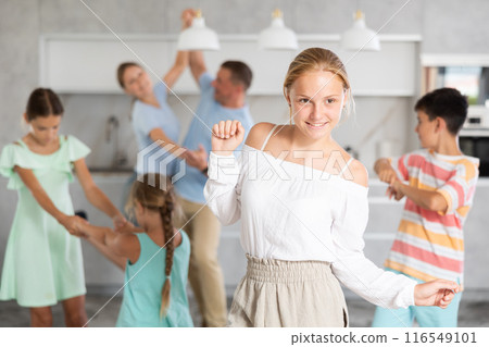 Behind cheerful girl, big family of parents, sisters, brother is rejoicing, dancing, having fun. 116549101