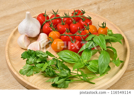Image of herbs and vegetables for Italian cuisine. Cherry tomatoes, Italian parsley, basil, garlic. 116549114