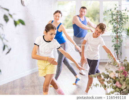 Positive pre-teenage dancers and parent doing dance workout during group class 116549118