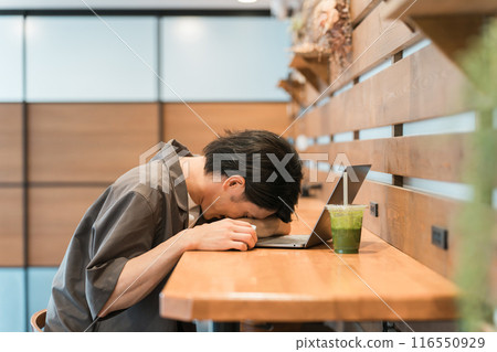 A young Asian man is shocked and depressed at a cafe/coworking space. A young Asian man is shocked and depressed at a cafe/coworking space. 116550929