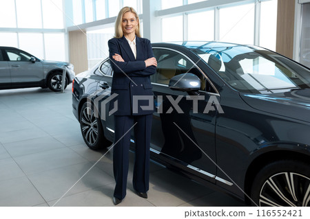 Female sale assistant in elegant suit in a car showroom 116552421
