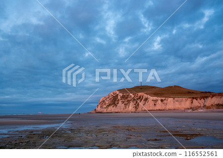 Enjoy a captivating view of a dramatic coastal sunset over a rocky cliff with a cloudy sky Enjoy a captivating view of a dramatic coastal sunset over a rocky cliff with a cloudy sky 116552561