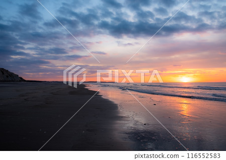 Witness a Breathtaking Sunrise at a Peaceful Beach with Lovely Sky Colors and Calm Reflection 116552583