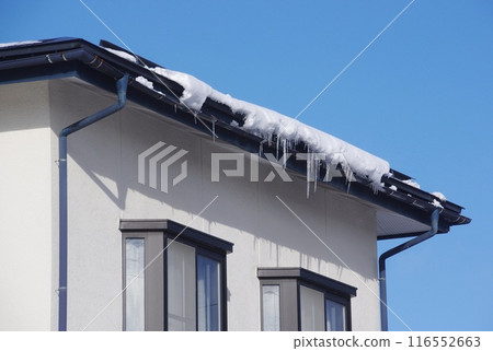Snow clumps hanging on rain gutters 116552663