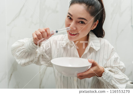 woman making nasal wash with using sryinge flushing inside nose 116553270