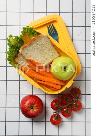 Yellow lunch box with fresh vegetables and fruits Yellow lunch box with fresh vegetables and fruits 116554212
