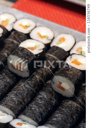 A tray with sushi rolls displayed on a vibrant red table A tray with sushi rolls displayed on a vibrant red table 116556749