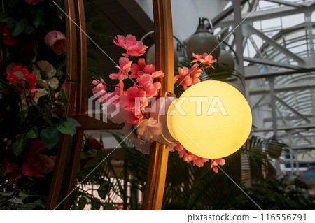 A decorative lamp adorned with pink flowers suspended from it A decorative lamp adorned with pink flowers suspended from it 116556791