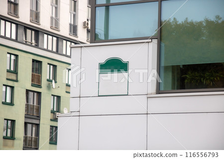 There is a white building with a green sign displayed on it 116556793