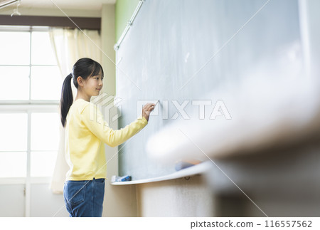 Female elementary school student writing on the blackboard 116557562