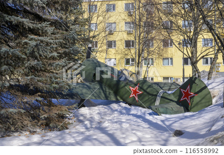 A military fighter aircraft from the Second World War made in the USSR in a park among melting snow A military fighter aircraft from the Second World War made in the USSR in a park among melting snow 116558992