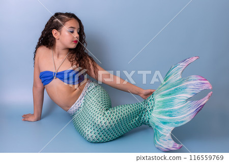 Adorable elegant girl in a mermaid costume, isolated on a blue background. Adorable elegant girl in a mermaid costume, isolated on a blue background. 116559769