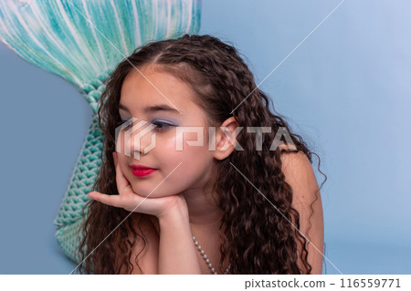 Close up of pretty girl in a mermaid costume lie on light-blue background Close up of pretty girl in a mermaid costume lie on light-blue background 116559771