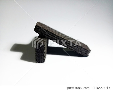 Dark brown wafer with cross shadow on isolated white background  116559913