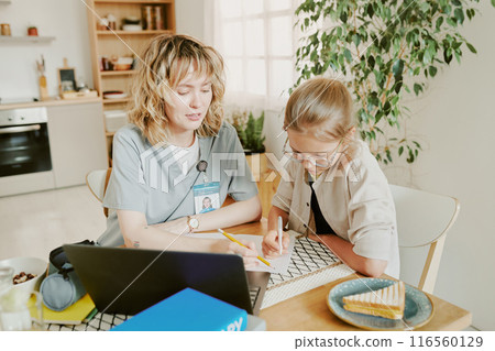Blonde Caucasian nurse mom and her golden haired daughter drawing together while having breakfast before workday 116560129