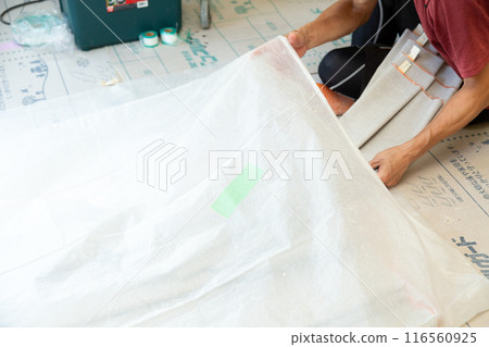 A craftsman laying wallpaper during the renovation of a used house 116560925
