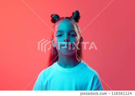 Portrait of beautiful young girl, child in white t-shirt, with hair styled in two buns posing with little smile against pink background in neon light Portrait of beautiful young girl, child in white t-shirt, with hair styled in two buns posing with little smile against pink background in neon light 116561124