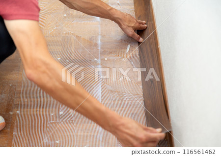 一名布藝工匠在翻新二手房時將地磚貼在走廊地板上。 116561462