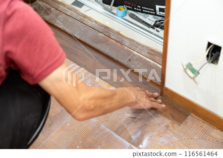 一名布藝工匠在翻新二手房時將地磚貼在走廊地板上。 116561464