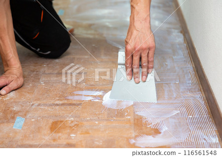 一名布藝工匠在翻新二手房時將地磚貼在走廊地板上。 116561548