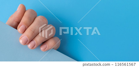 Woman manicured hands, stylish beige nails. Mock up template copy space Closeup of manicured nails of female hand in blue sweater in blue background. Winter or autumn style of nail design concept 116561567
