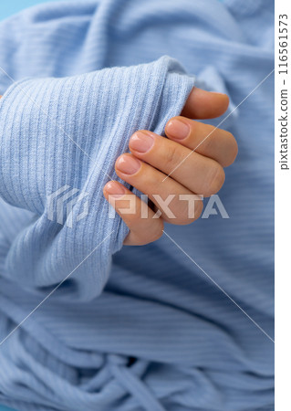 Stylish nude beige female nails on blue sweater background. Modern trendy stylish Beautiful manicure. Cute pastel nail minimalistic design concept of beauty treatment. Gel nails. Skin care 116561573