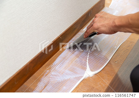 A wallpaper craftsman laying floor tiles on the hallway floor during the renovation of a used house A wallpaper craftsman laying floor tiles on the hallway floor during the renovation of a used house 116561747