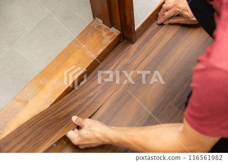 A wallpaper craftsman laying floor tiles on the hallway floor during the renovation of a used house A wallpaper craftsman laying floor tiles on the hallway floor during the renovation of a used house 116561982