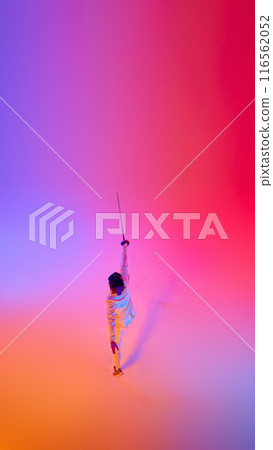 Aerial view of sportsman, fencer during battle leaping with sword in motion in mixed neon lights against gradient studio background. 116562052