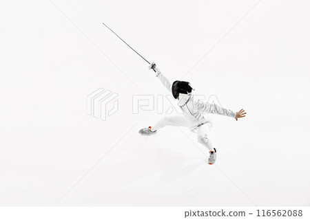 Fencer in full white attire, including mask, depicted mid-lunge with rapier held aloft against white studio background. 116562088