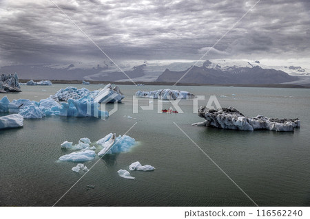 Group of athletes kayaking around melting icebergs in iceland Group of athletes kayaking around melting icebergs in iceland 116562240