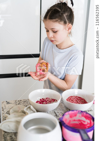 With focused attention, this budding culinary artist dips pretzels into a pot of melted chocolate, creating sweet delights in the warmth of a well-lit home kitchen. With focused attention, this budding culinary artist dips pretzels into a pot of melted chocolate, creating sweet delights in the warmth of a well-lit home kitchen. 116562395