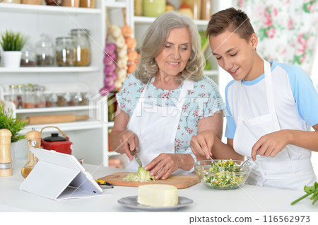 Grandmother and grandson preparing salad in the kitchen Grandmother and grandson preparing salad in the kitchen 116562973